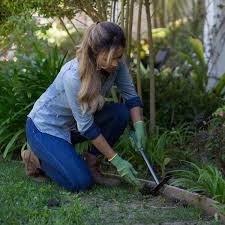 woman properly kneeling while tending her garden, demonstrating proper gardening ergonomics for Carolina Physical Therapy. 