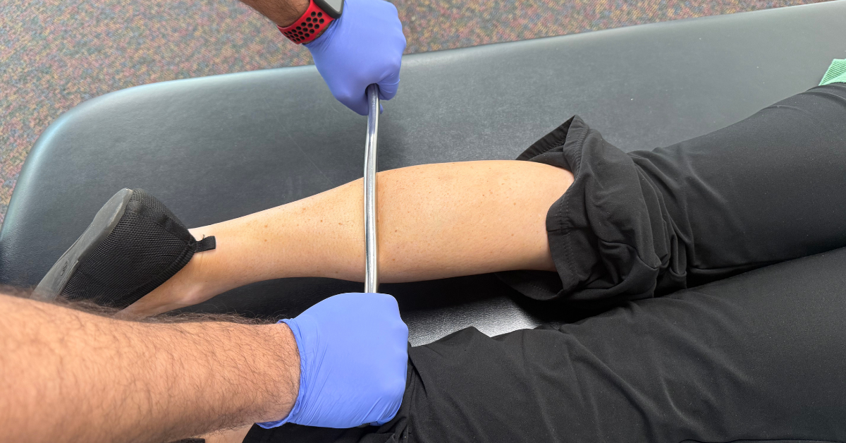 Matthew, a Physical Therapist Assistant at Carolina Physical Therapy, performing the Graston Technique on a patient's calf to reduce soft tissue restrictions.